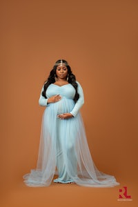 a pregnant woman in a blue dress posing for a photo