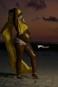 a pregnant woman in a yellow dress on the beach
