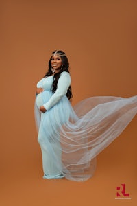 a pregnant woman in a blue dress posing for a photo